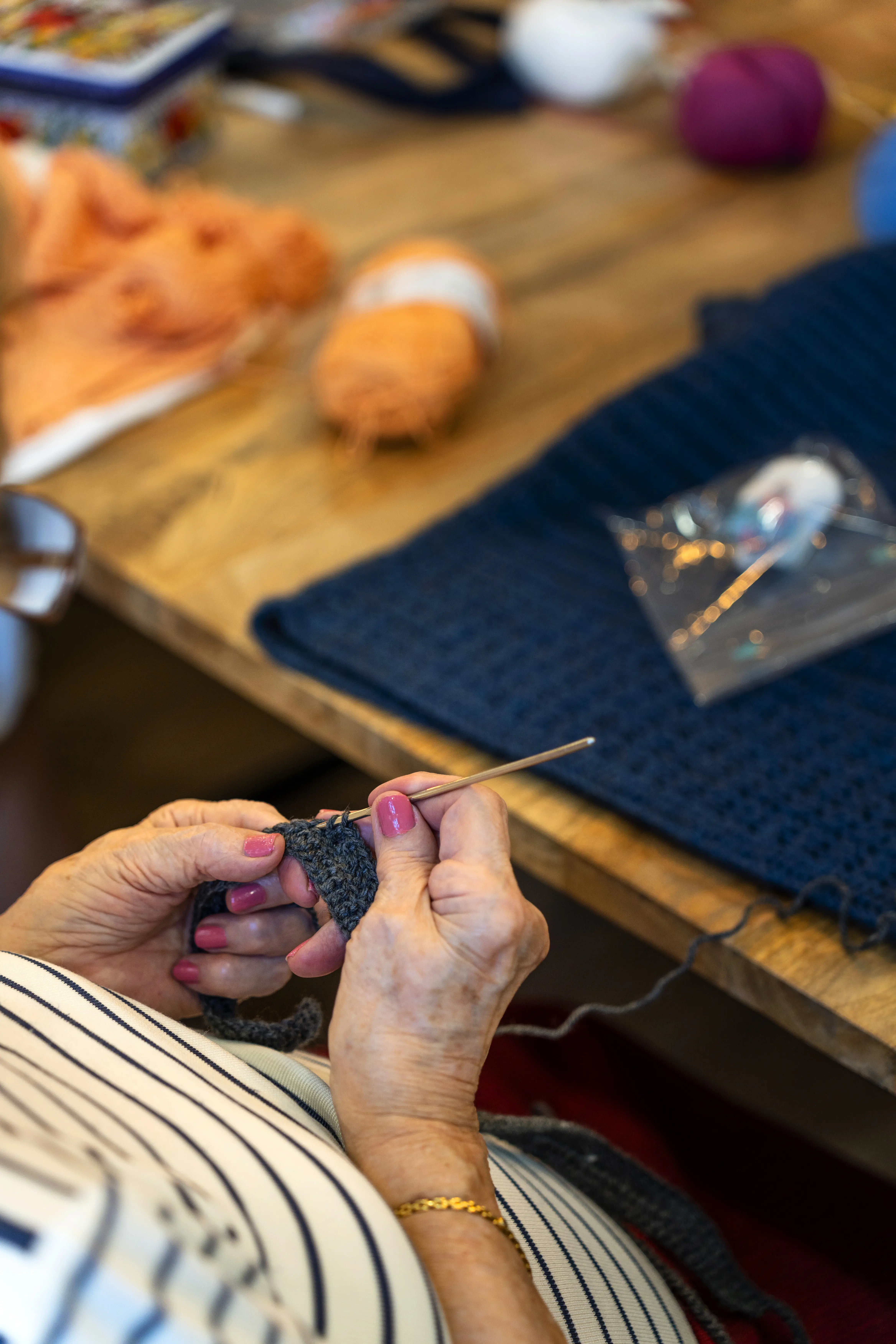 Häkelclub: Eine ältere Frau strickt einen Schal für ihre Enkelin.